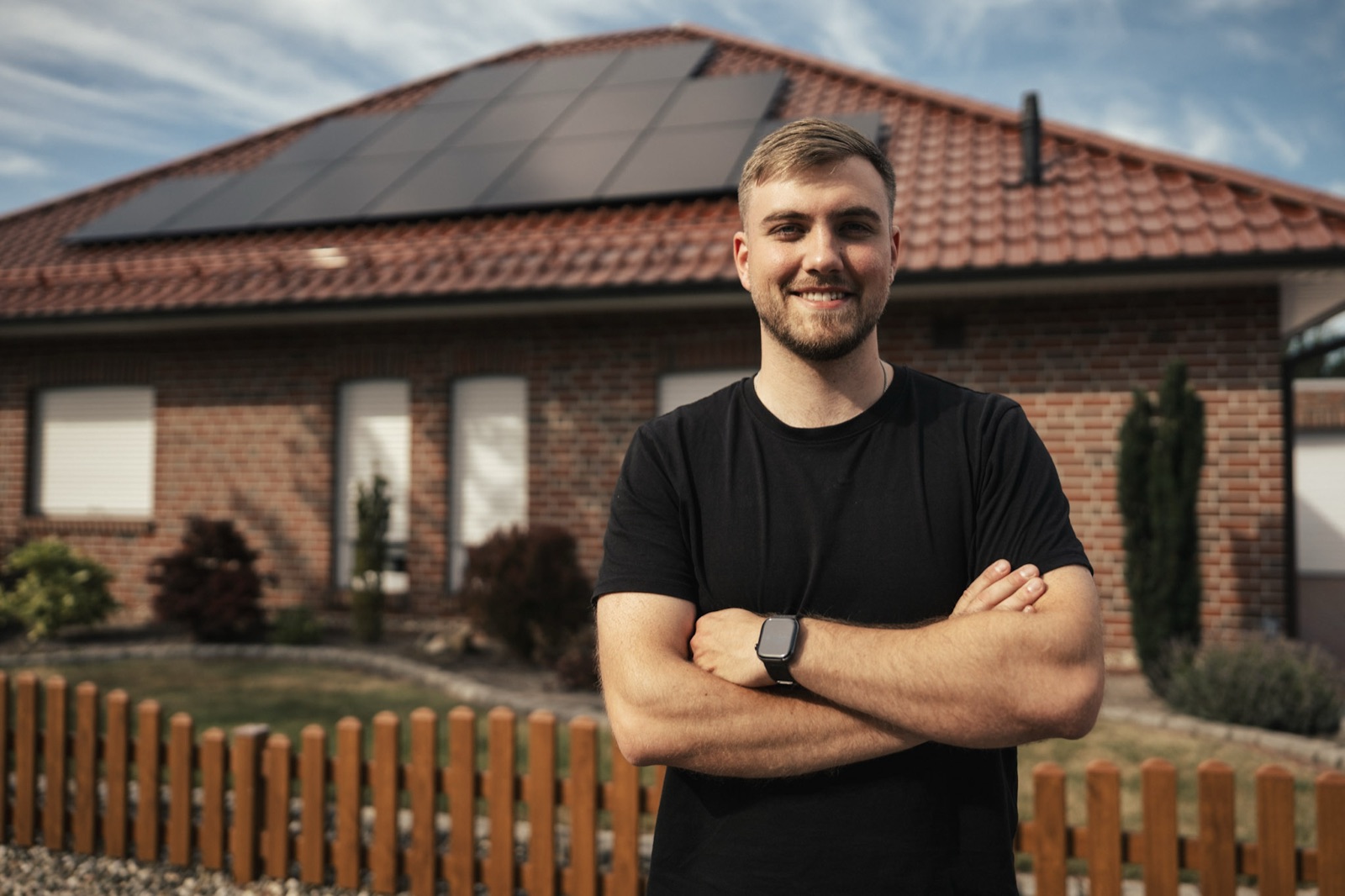 Maik Root vor einem Einfamilienhaus mit installierter Photovoltaikanlage auf dem Dach