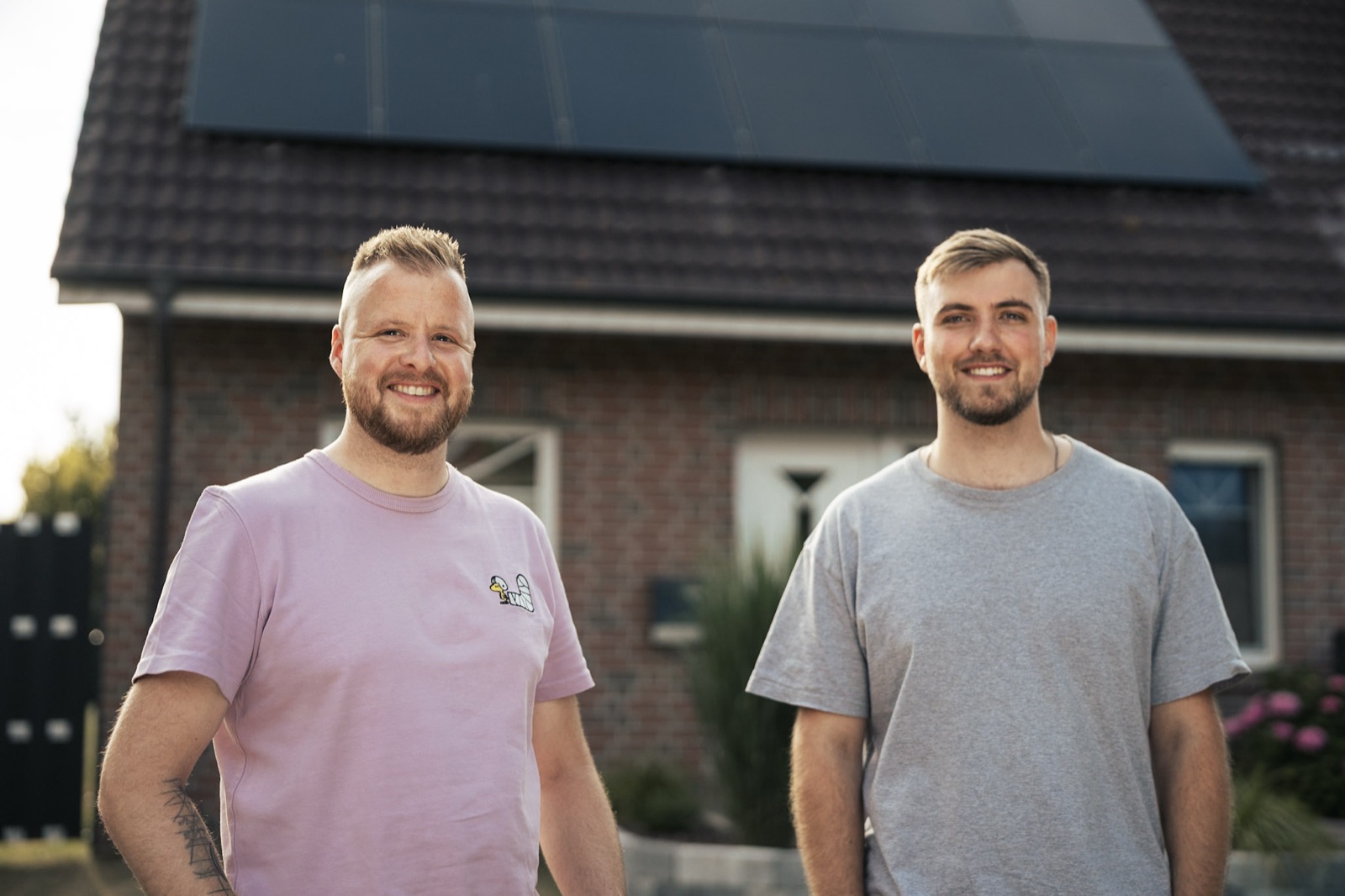 Zwei Mitarbeiter von Root Elektrotechnik vor einem Einfamilienhaus mit Photovoltaikanlage